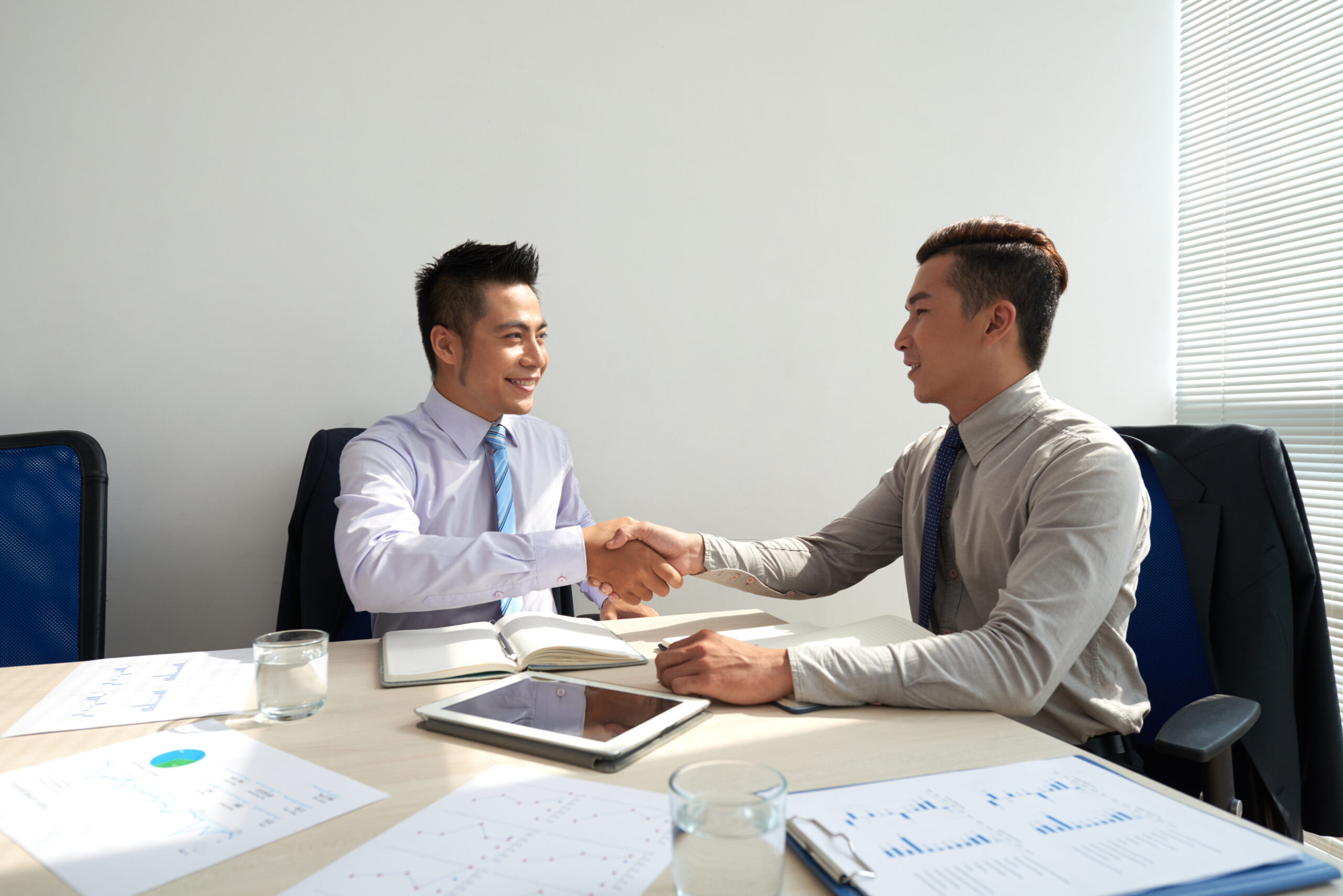 Cheerful Asian business executive shaking hands after conversation